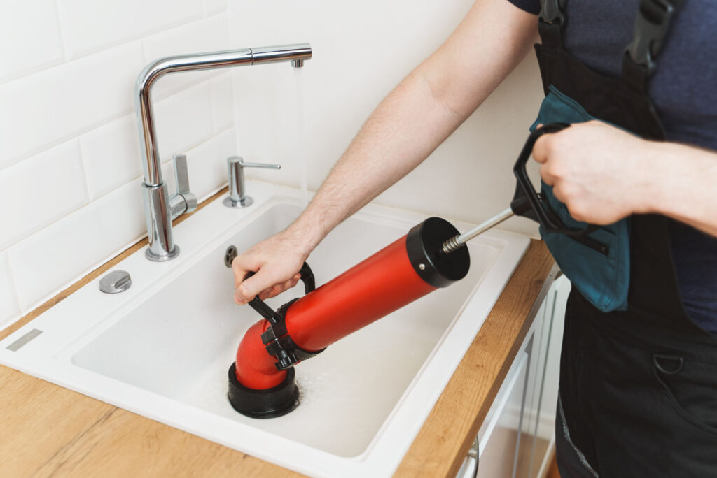 Klempner befreit Küchenspüle mit professionellem Pumpenreiniger von Verstopfungen.